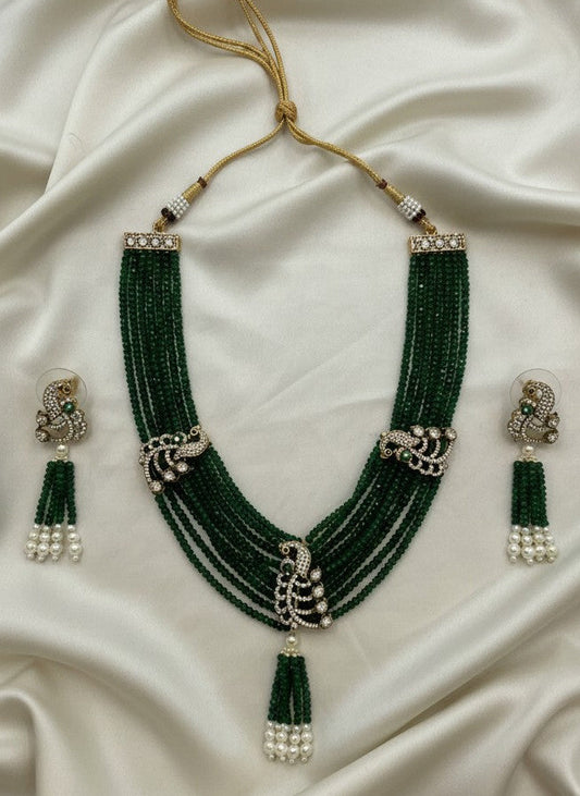 Green beaded necklace with matching earrings on a white fabric background