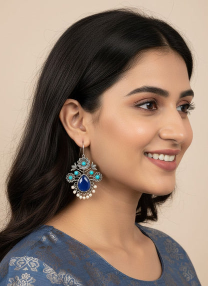 Model wearing Silver Oxidized Floral Drop Earrings with Dark Blue Aqua Monalisa Stones & Pearl Cluster Detailing for Women - Office & Casual Wear