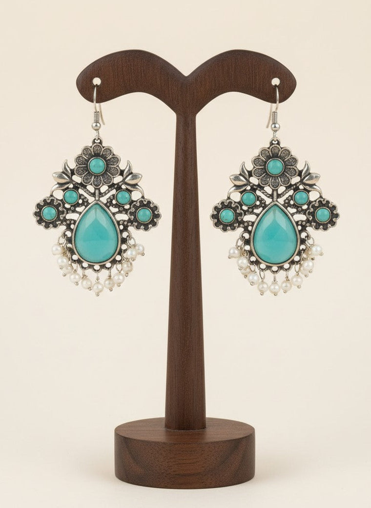 On a display stand Silver Oxidized Floral Drop Earrings with Mint Stones & Pearl Cluster Detailing for Women - Office & Casual Wear 